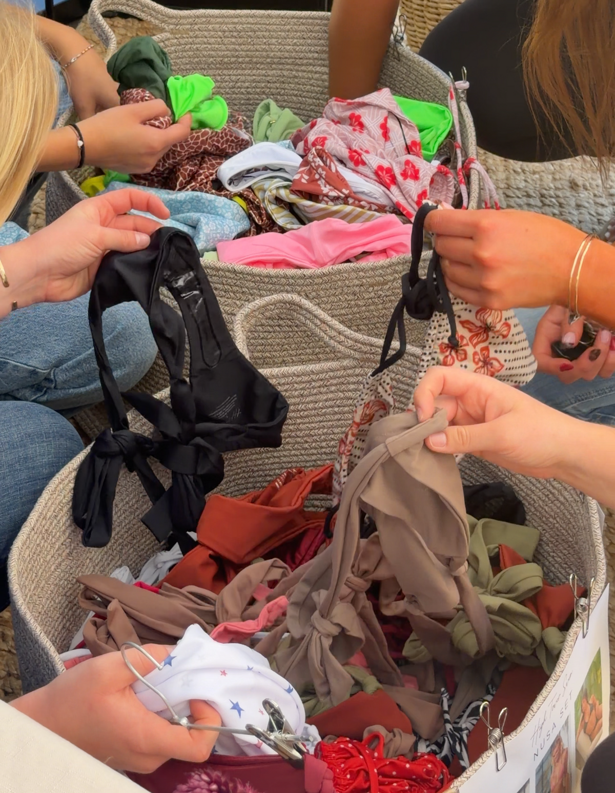 Sorority members browsing colorful High Tower Swimwear bikinis together at a college pop-up event